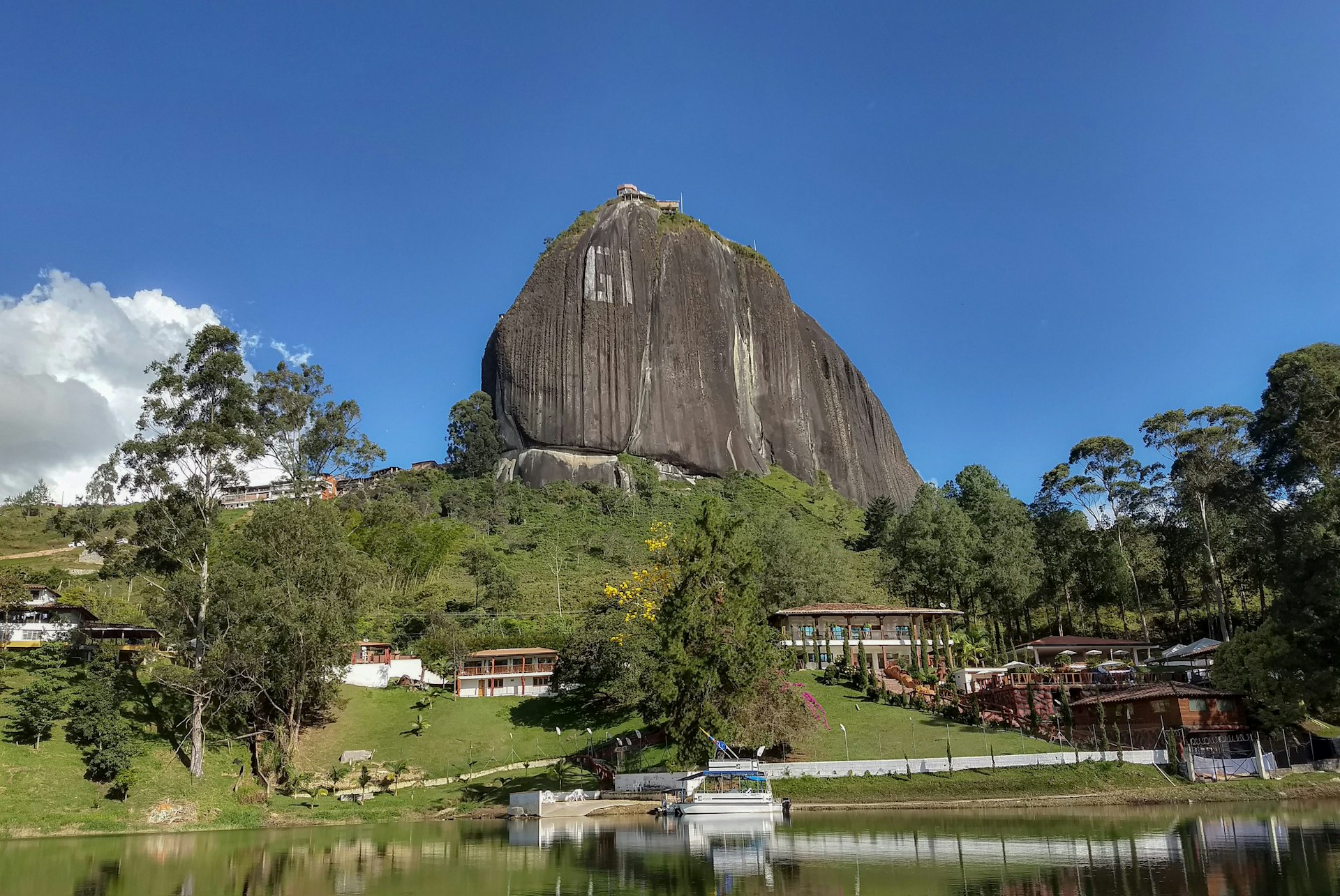 a large rock sitting on top of a lush green hillside